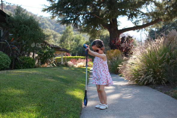 Young girl using a grabber tool to pick up trash in the neighborhood