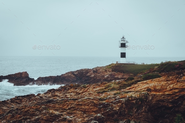 Lighthouse in the shoreline on a misty day. Atmospheric mood. Scenery. Seascape.