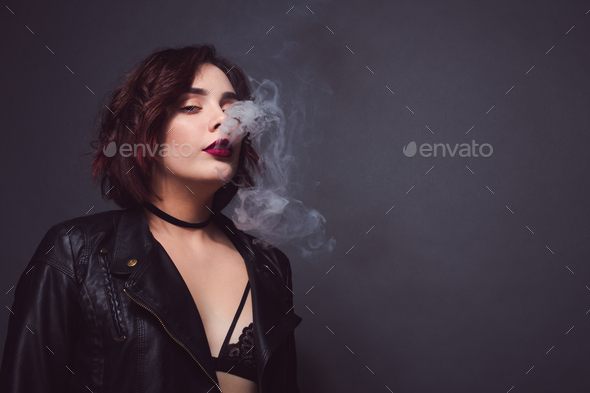 Stylish female breathing out smoke