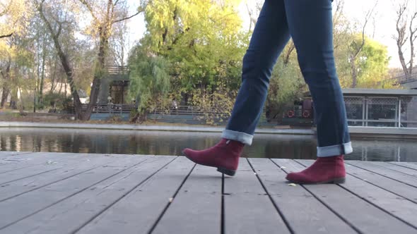 Female Legs in Burgundy Boots and Blue Jeans Climb the Stone Stairs alt