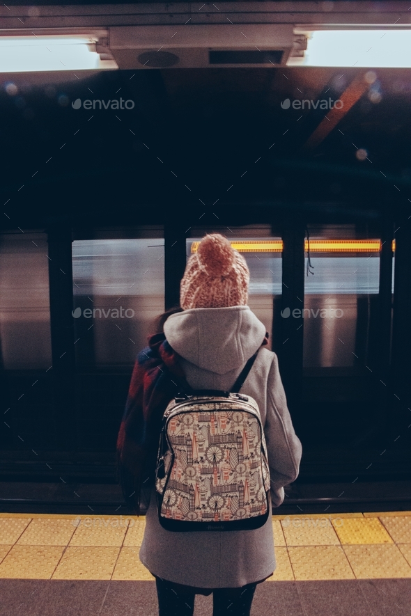 Urban scene of a millenial woman in a subway station. Motion blur. People and life. Winter fashion.