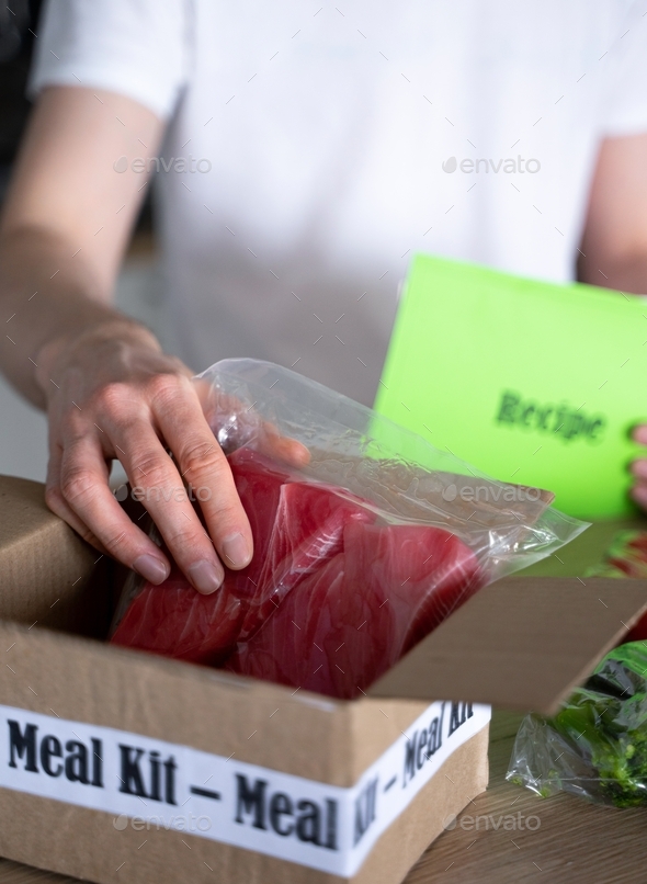 Man Unpack Online Home Food Delivery. Box with packed tuna, shrimp, vegetables and recipe card