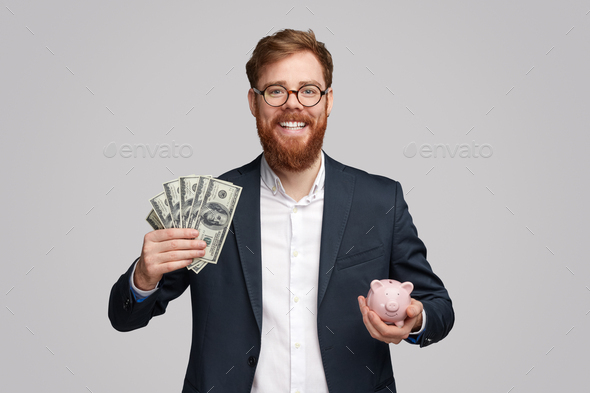Cheerful businessman with cash and piggy bank