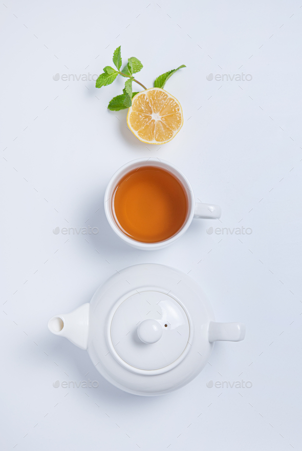 Cup of tea and teapot with lemon and mint on white background. Top view