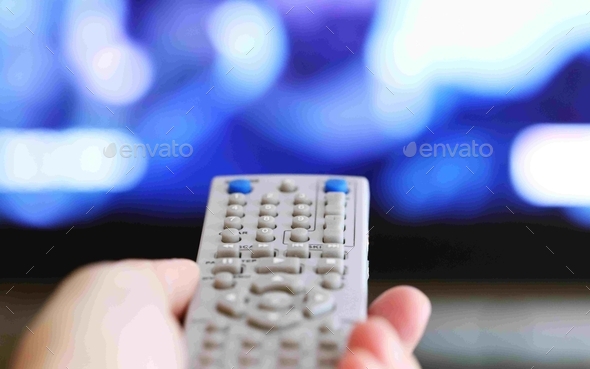 People holding television remote control in hand closeup blur tv background