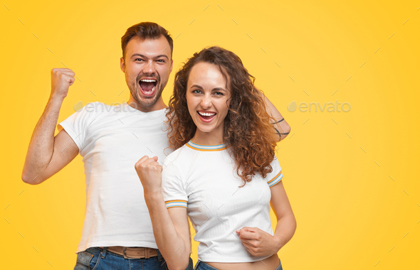 Young successful couple holding fists up