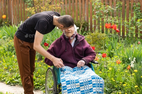 Senior care assistant with very old disabled woman in nursing home.