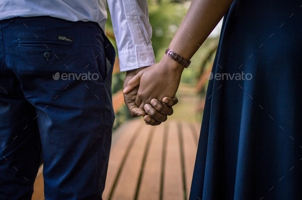 Young couple holding hands crossing a bridge