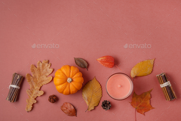 Autumn composition with pumpkins, candle and leaves on red background. Top view, copy space