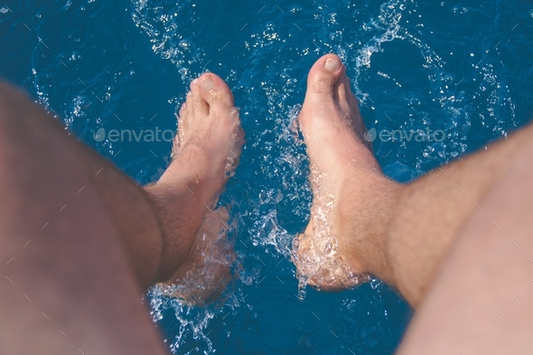 Human male legs feet in water summer