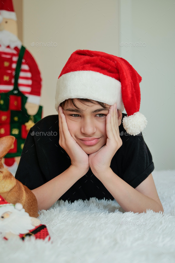 a teenager in a Santa Claus hat lies on a bed against the background of the advent calendar - Stock Photo - Images