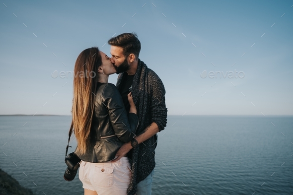 Couple kissing on the edge of a cliff with a big lake behind