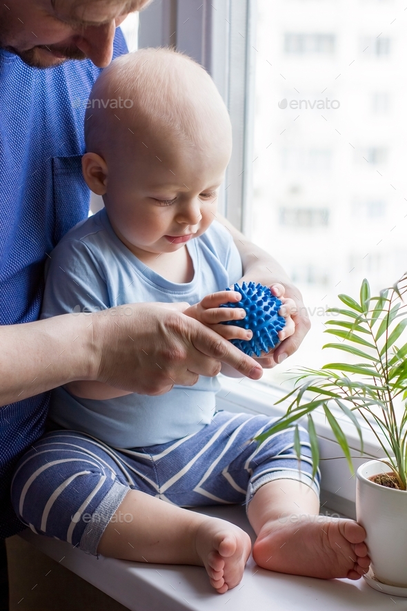 Father with cute baby boy toddler which hold prickly massage ball.