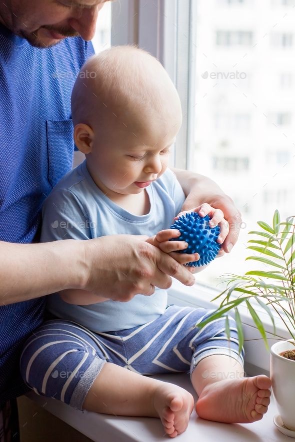 Father with cute baby boy toddler which hold prickly massage ball.