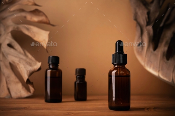 Closeup of small bottles of amber essential oil on a wooden fence under the  sunlight Stock Photo by wirestock