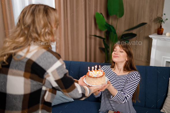 Birthday woman with closed eyes makes a wish and prepares to blow out the candles on the cake