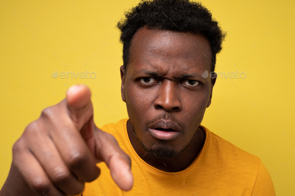 African american guy in yellow casual t-shirt discovering hidden camera