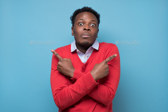 African man pointing in two different directions, not sure which way to go