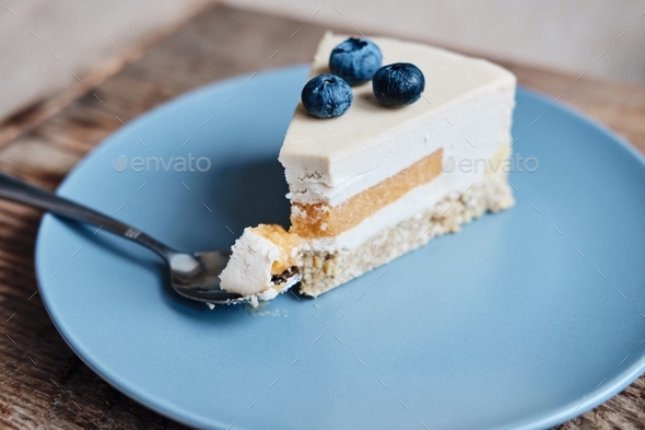 a piece of gluten-free cake with blueberries on a spoon close-up. Gluten free cake on a blue plate