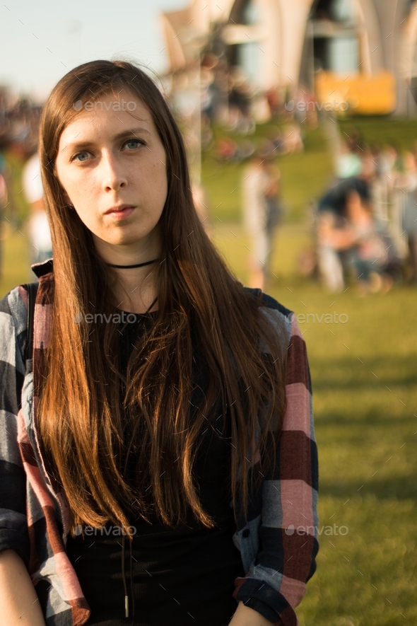 portrait of a girl with long hair in the afternoon outdoors in summer. serious girl in the crowd.