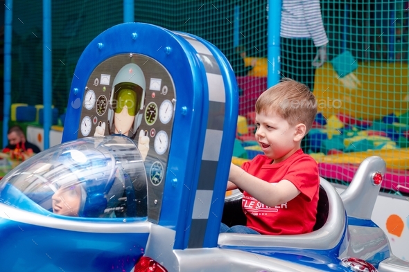 the little boy plays on the rides. Children's playroom. The kid is ...