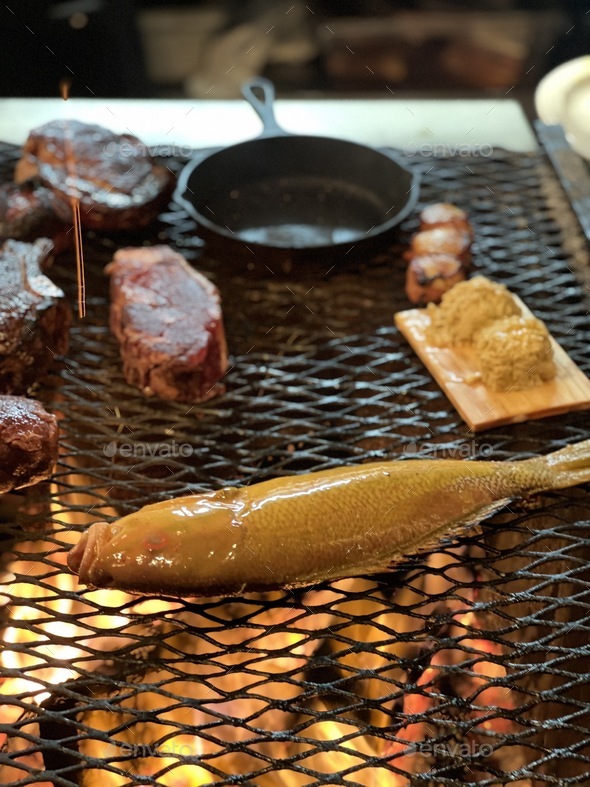 Fish and steak cooking over an open fire grill Stock Photo by