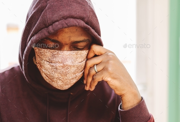 African American or black man wearing face mask looking depressed, sad, or anxious