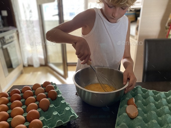 Caucasian boy cooking with mother, make omelet, cake, eggs at the kitchen, helping