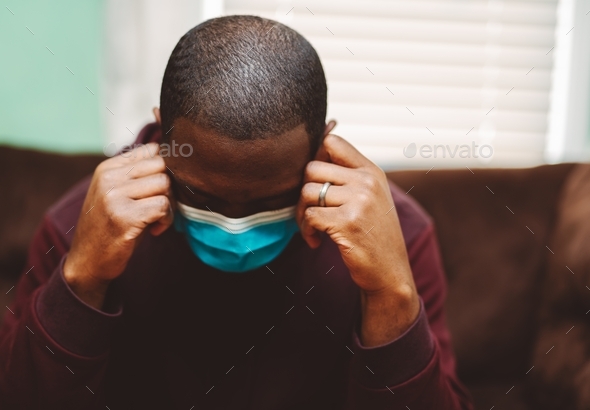 African American or black man wearing face mask looking depressed, sad, or anxious