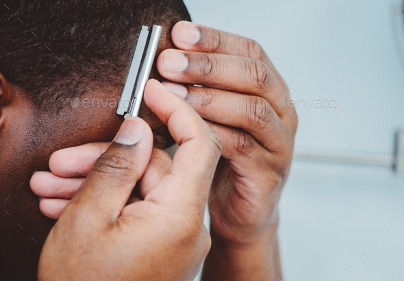 African American or black man at home shaving hair with razor blade ...