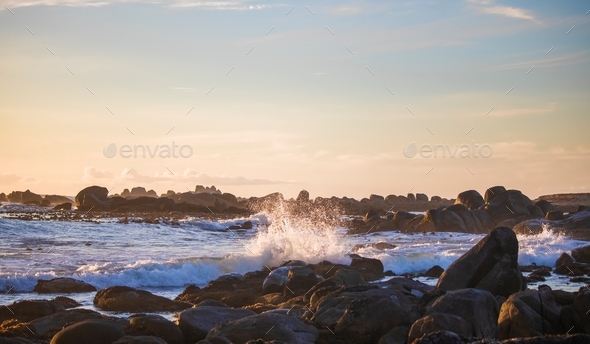 Dreamy ocean waves crashing on a rocky beach at sunset in Jacobsbaai, South Africa. - Stock Photo - Images