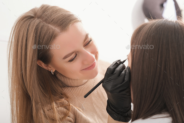 beautiful woman make up artist painting brows for client in beauty salon. make up for model,