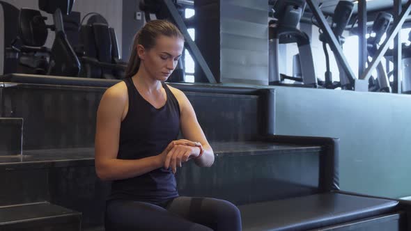 A Fit Girl Turns on a Second Hand Watch for Sports Exercises on a Wristwatch alt