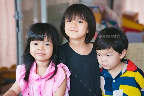 Three sibling held a photo together. Asian cute girl smiles sweetly.