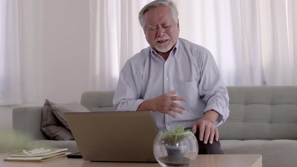 Asian Elderly man Chest pain due to heart disease on the sofa in the living room. alt