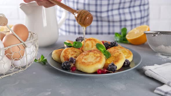 Honey pouring on cottage cheese fritters, sweet fried cheese pancakes or cheesecakes