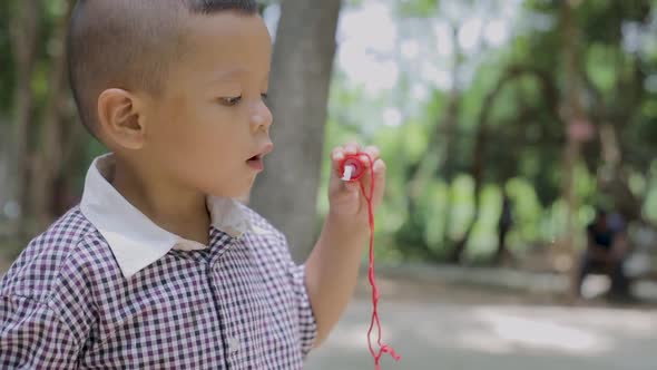 Asian boy blowing bubbles in the front yard