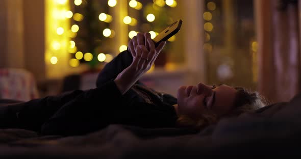 Woman Is Chatting in the Smartphone on the Bed