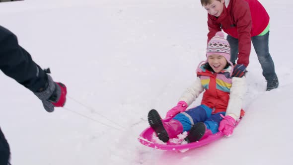 Kids playing and pushing sled in winter snow