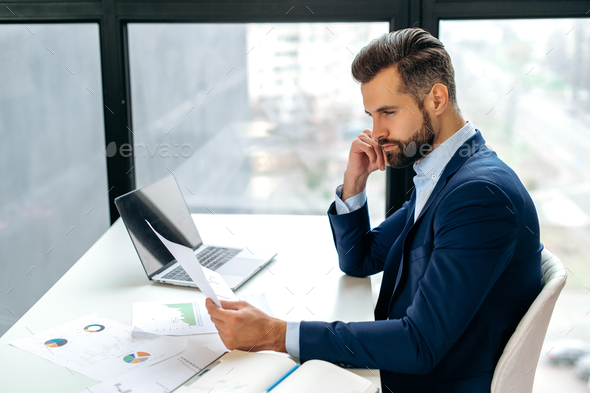 Serious focused smart caucasian business man, company ceo, financial director, sits at a work desk