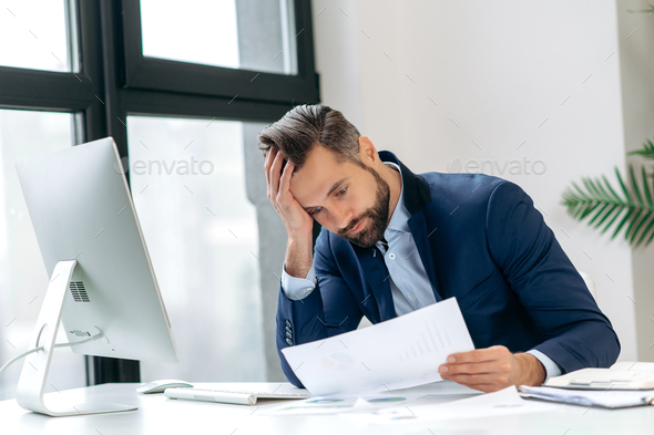 Frustrated dazed caucasian man, company employee, product manager, ceo, sitting at workplace in the