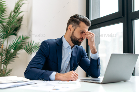 Frustrated overworked caucasian businessman, entrepreneur, product manager, programmer, sits at a