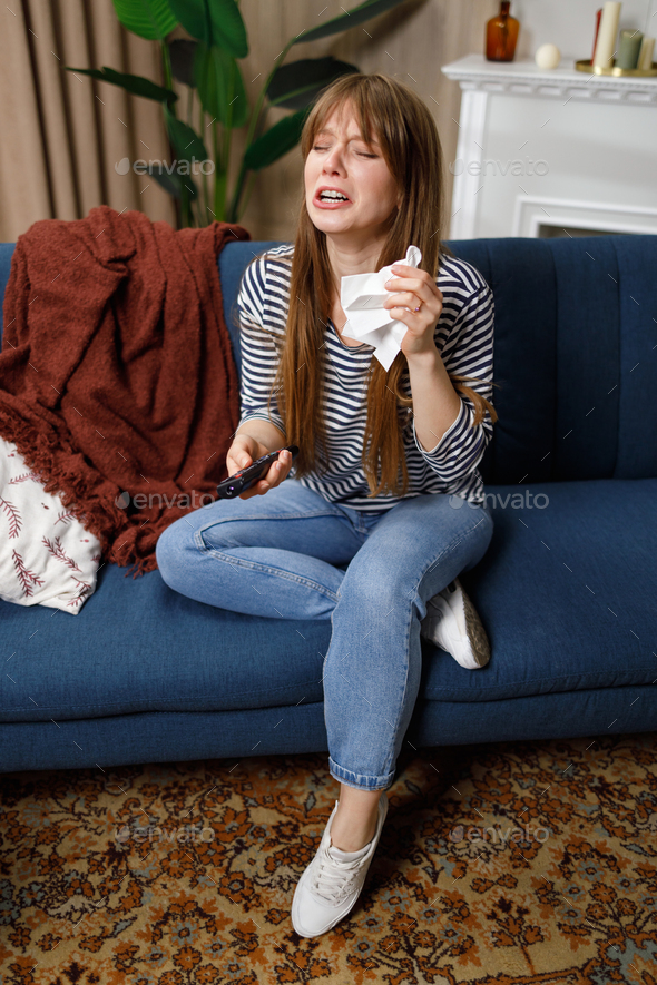 Young caucasian woman in hysterics while watching drama movie at home