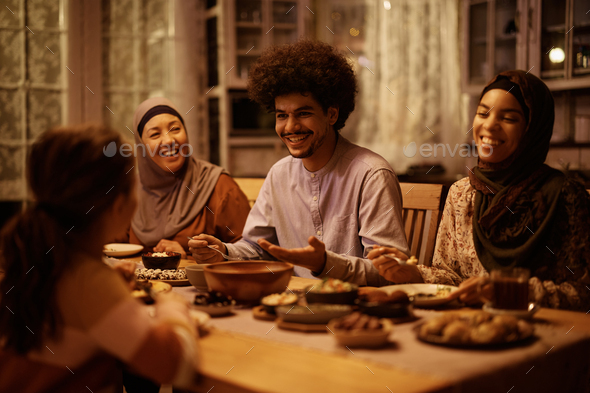 Happy Middle Eastern family enjoying in conversation during Ramadan meal at dining table.