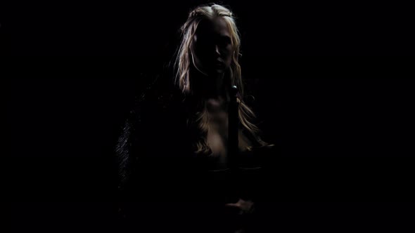 Medieval Princess with a Sword in Hand, Wearing a Fur Coat, Standing in the Dark alt