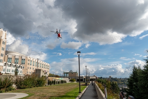 Medical helicopter flying over landing zone at hospital.