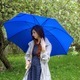Young woman teenager in park with blue umbrella having moment in nature by Spring floral apple tree - PhotoDune Item for Sale