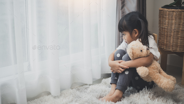 lonely little girl hugging toy, sitting at home alone, upset unhappy child waiting for parents,