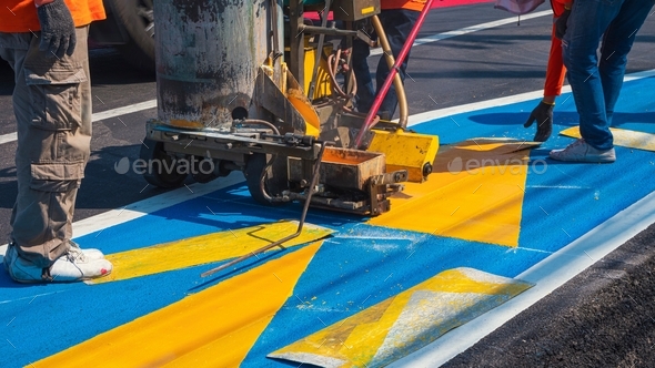 Road workers group with thermoplastic marking machine painting traffic lines and bike lane on street