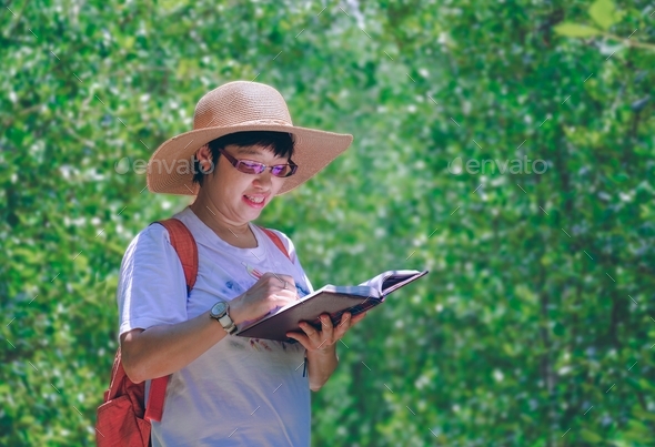 Portrait of female tourist taking notes during ecotourism in mangrove forest at natural parkland